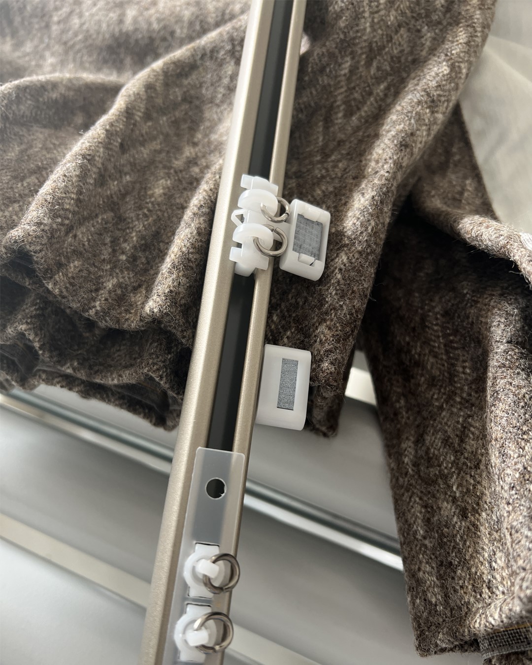 Detaljbilde av Nexty gardinskinne i fargen Champagne med gardinstoppere og glidere. Fra sømstudio hos Gardinmaker.no. Foto. Detaljbilde av Nexty gardinskinne i fargen Champagne med gardinstoppere og glidere. Fra sømstudio hos Gardinmaker.no. Foto.