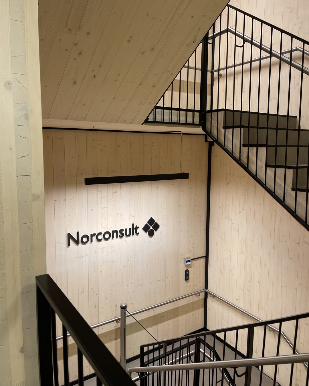 Trappeoppgang i kontorlokalet til Norconsult i Larvik. Sort rekkverk, lyst paner på veggene. Foto. Trappeoppgang i kontorlokalet til Norconsult i Larvik. Sort rekkverk, lyst paner på veggene. Foto.