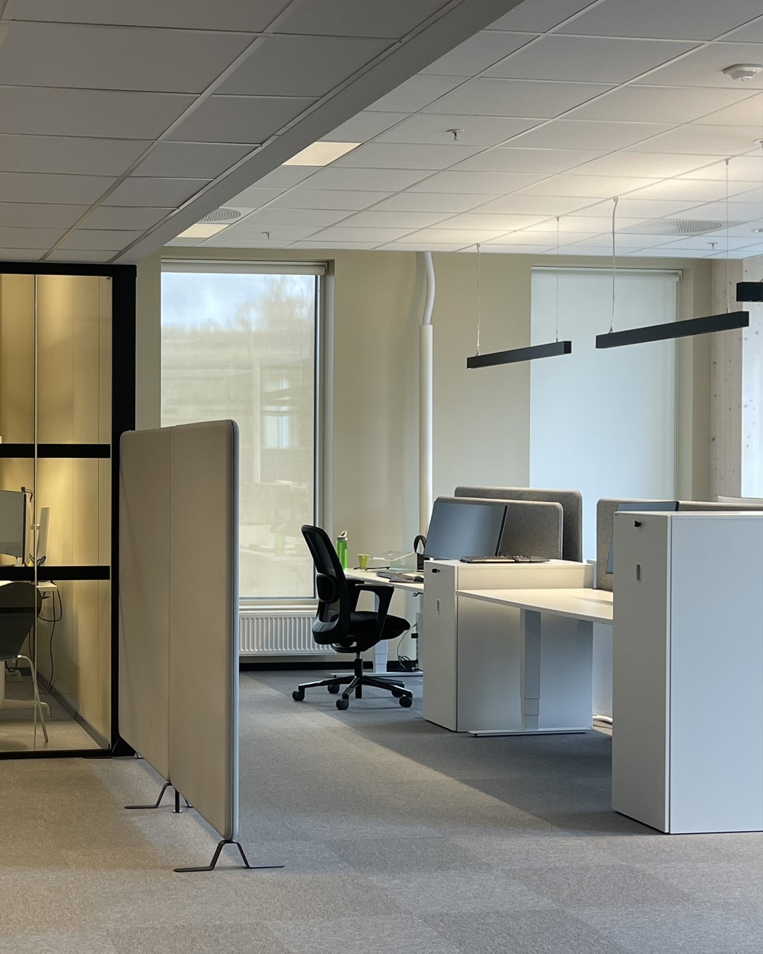 Moderne kontor i lys beige vegger med hvit kontorpult og sort stor. Vindu med rullegardin Screen Vision 5% fra Mermet i fargen White Linen. Foto. Moderne kontor i lys beige vegger med hvit kontorpult og sort stor. Vindu med rullegardin Screen Vision 5% fra Mermet i fargen White Linen. Foto.