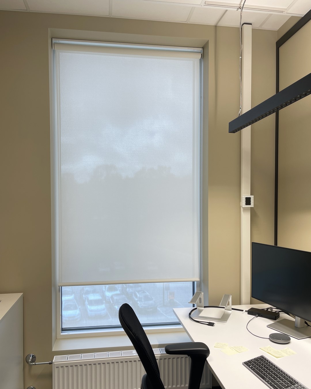 Moderne kontor i lys beige vegger med hvit kontorpult og sort stor. Vindu med rullegardin Screen Vision 5% fra Mermet i fargen White Linen. Foto. Moderne kontor i lys beige vegger med hvit kontorpult og sort stor. Vindu med rullegardin Screen Vision 5% fra Mermet i fargen White Linen. Foto.