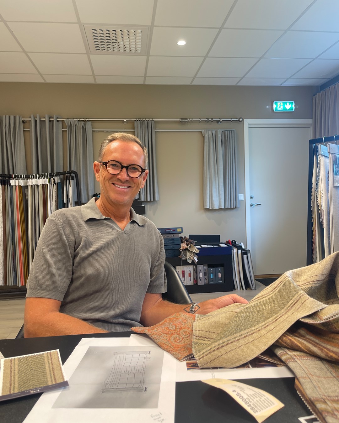 Halvor Bakke velger tekstiler til gardinløsningen, med ulike mønstrede stoffprøver foran seg i Gardinmakers showroom. Fra Eventyrlig Oppussing Mesnali. Foto.
