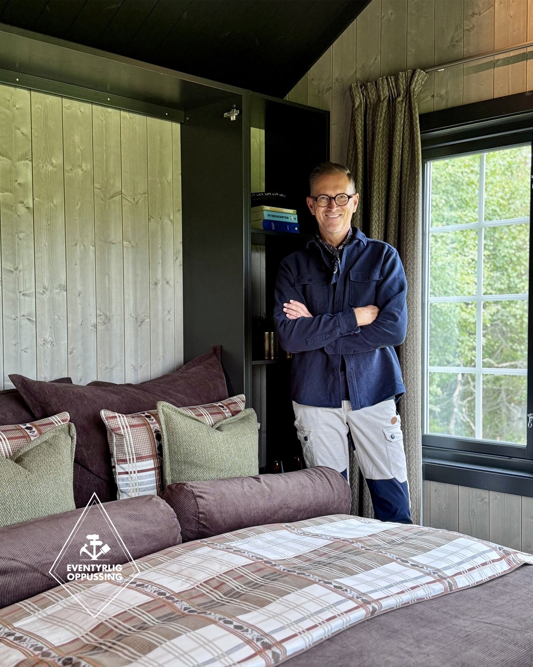 Halvor Bakke i annekset på Almoseteren. Soverom med oppredd seng, sengetøy og tekstiler i mørk dus lilla, grønne duse farger samt ruter. Lyse panelvegger og sort hylleløsning rundt sengen. Vindu med sortmalte lister. Ullgardiner i blyantfold. Fra Eventyrlig Oppussing 2025, Almoseteren i Snåsa. Foto. Halvor Bakke i annekset på Almoseteren. Soverom med oppredd seng, sengetøy og tekstiler i mørk dus lilla, grønne duse farger samt ruter. Lyse panelvegger og sort hylleløsning rundt sengen. Vindu med sortmalte lister. Ullgardiner i blyantfold. Fra Eventyrlig Oppussing 2025, Almoseteren i Snåsa. Foto.