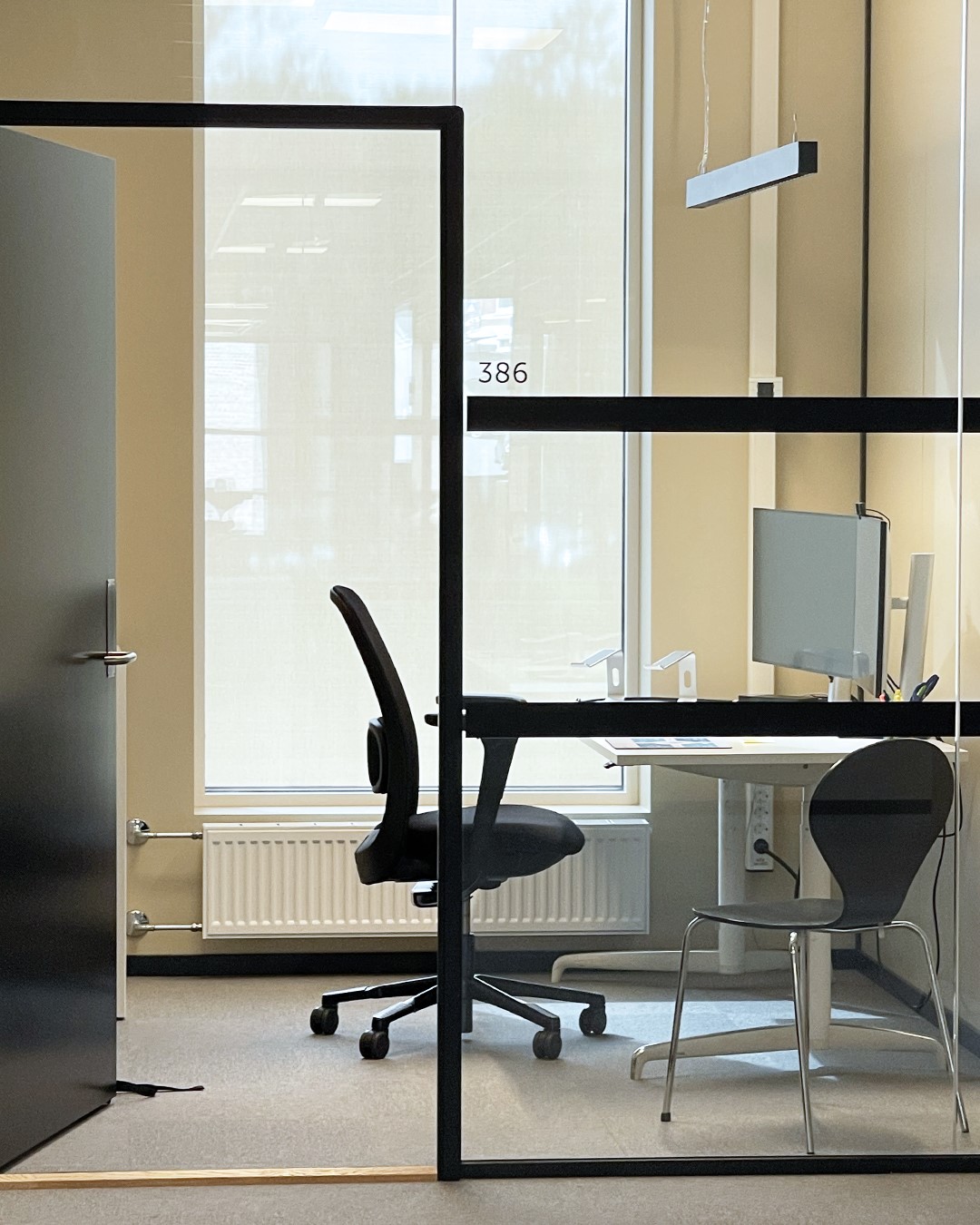 Moderne kontor i lys beige vegger med hvit kontorpult og sort stor. Vindu med rullegardin Screen Vision 5% fra Mermet i fargen White Linen. Foto. Moderne kontor i lys beige vegger med hvit kontorpult og sort stor. Vindu med rullegardin Screen Vision 5% fra Mermet i fargen White Linen. Foto.