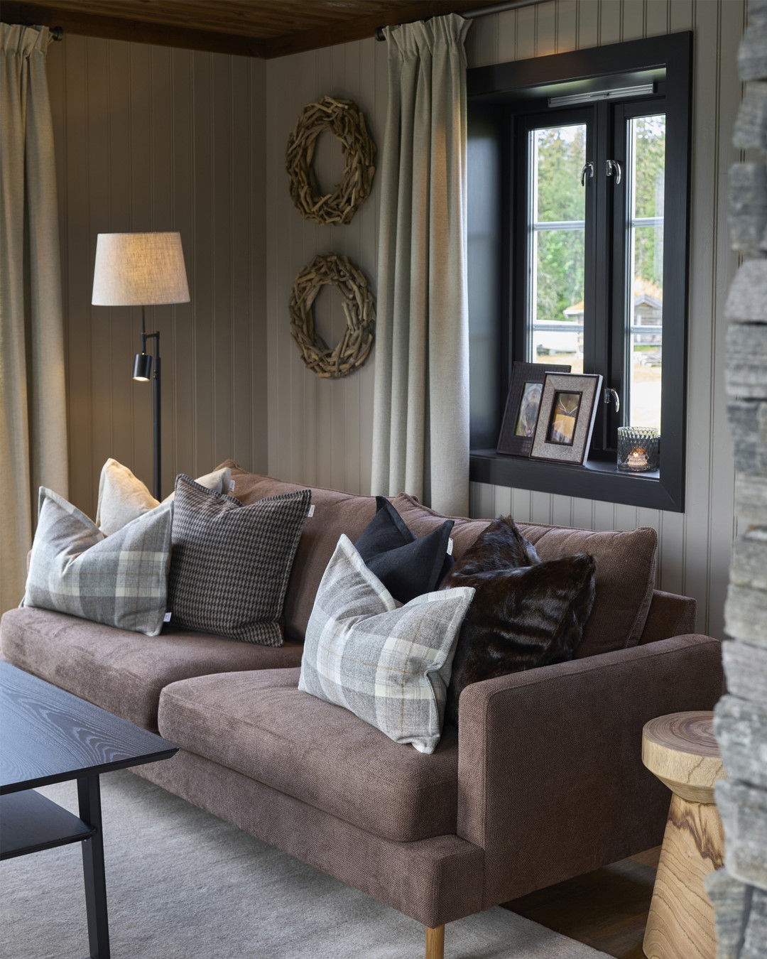 Stua på Almoseteren. Stor skiferkledd peis deler av stue og spisestue. Varmt tregulv og tak. Lyse vegger. Vindu med sortemalte lister. Skreddersydde gardiner i blyantfold i lys beige tekstil fra Roma. Dus plommefarget sofa med puter i ulike tekstiler og farger. Fra Eventyrlig Oppussing 2025, Almoseteren i Snåsa. Foto. Stua på Almoseteren. Stor skiferkledd peis deler av stue og spisestue. Varmt tregulv og tak. Lyse vegger. Vindu med sortemalte lister. Skreddersydde gardiner i blyantfold i lys beige tekstil fra Roma. Dus plommefarget sofa med puter i ulike tekstiler og farger. Fra Eventyrlig Oppussing 2025, Almoseteren i Snåsa. Foto.